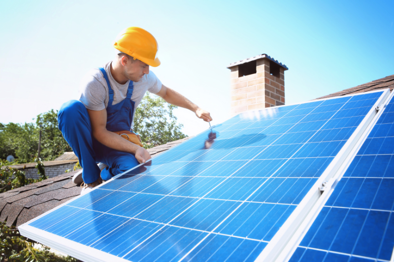artisan posant des panneaux solaires sur un toit